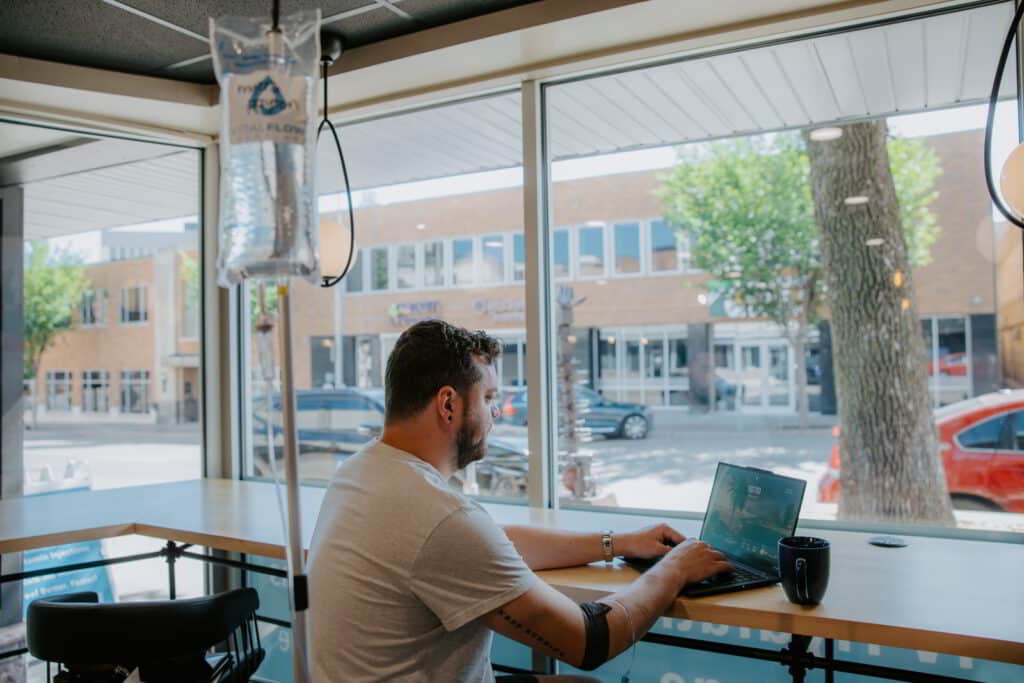 Client working on a laptop at the window bar during an IV drip at Vital Flow Infusions.