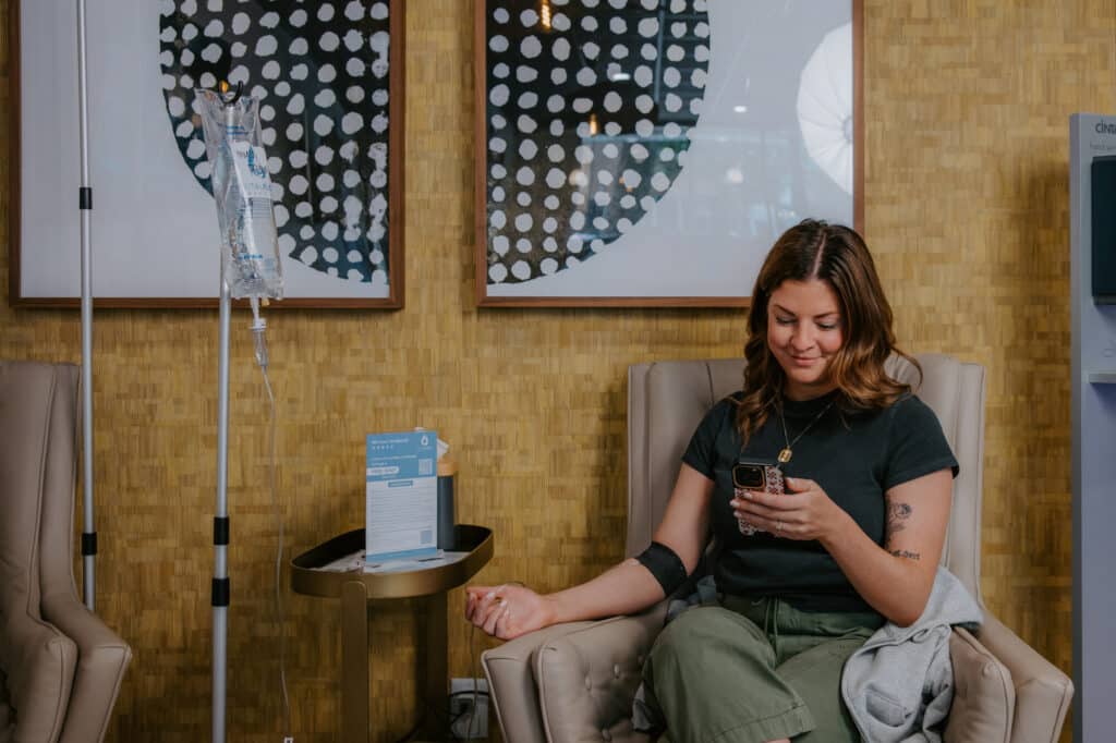 Client relaxing with her phone in a comfortable chair at Vital Flow Infusions in Sioux Falls.